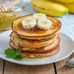 Stack of pancakes with banana and honey