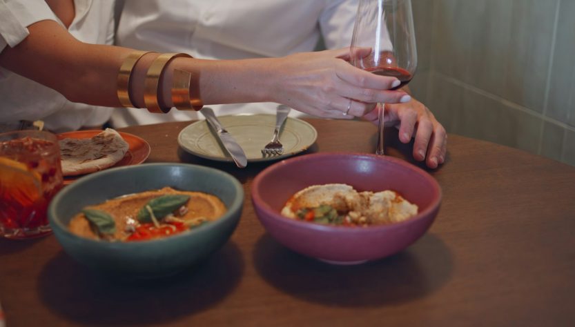 Woman hand holding wineglass at cafe closeup. Spouses tasting lebanese cuisine